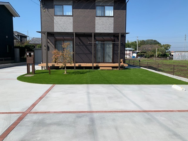 熊谷市の新築外構施工後の完成写真。人工芝・ウッドデッキ・駐車場の土間コンクリートで整備された庭
